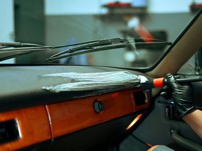 Detailing brush working foam into the dashboard of a classic car with wood trim
